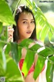 A woman in a red bikini standing in front of a plant.