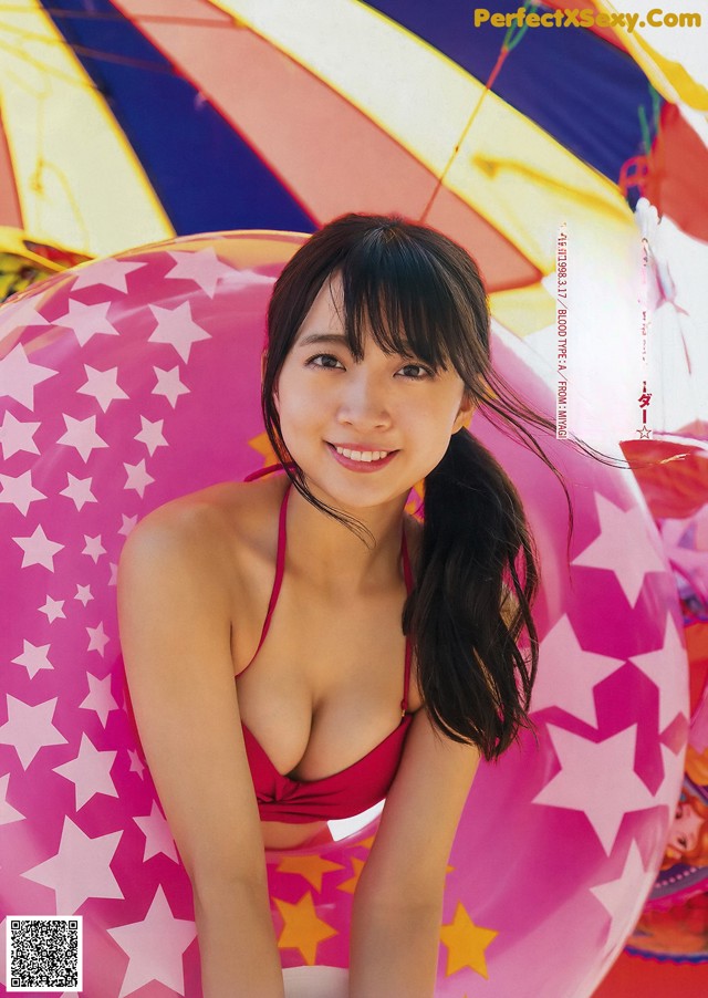 A woman in a red bikini sitting on an inflatable pool float.