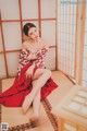 A woman in a red and white kimono sitting on the floor.