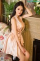 A woman in a pink dress posing in front of a fireplace.