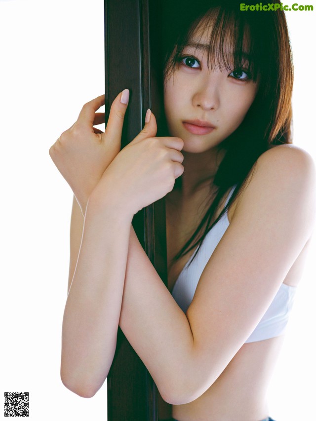 A young woman leaning against a wooden pole.