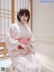 A woman in a pink kimono sitting on the floor.