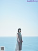 A woman standing on top of a cliff next to the ocean.