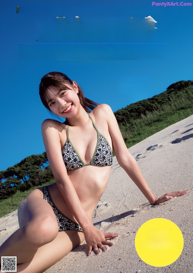 A woman in a bikini sitting on a beach.