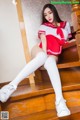 A woman in a red and white uniform is sitting on some stairs.