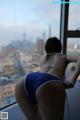 A woman in a blue bikini standing in front of a window.