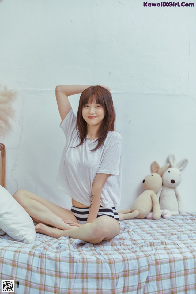 A woman sitting on a bed with a teddy bear.
