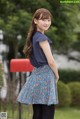 A young woman standing in front of a red mailbox.